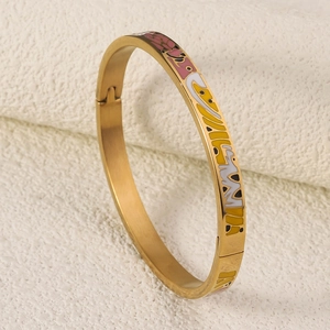 Detail view of gold titanium enamel bangle featuring a secure side clasp and floral patterns