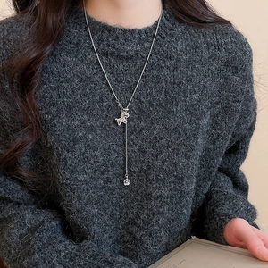 Silver long sweater chain with zircon horse and flower pendant on grey knitwear