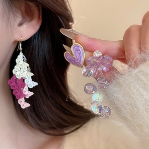 Macro shot of embroidered butterfly charms and purple heart crystal earrings for women