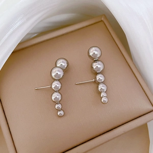 Minimalist silver titanium steel earrings with six graduated beads on a jewelry box