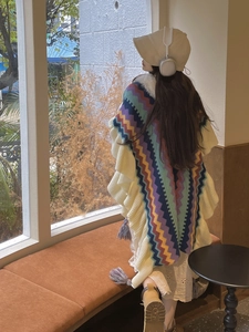 Detail view of colorful wave pattern knitted poncho with elegant fringe on model back