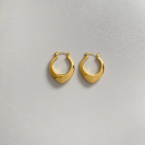 Detailed close-up of gold plated hollow oval earrings on light gray textured surface