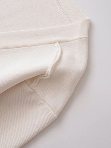 Macro shot of cream V-neck knit cardigan showing dense bandage texture and fine stitching