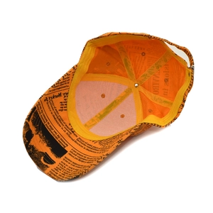 Detail of the newspaper print baseball cap showing interior lining and adjustable buckle