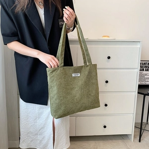 Macro detail of green corduroy tote bag featuring a minimalist Fashion label patch