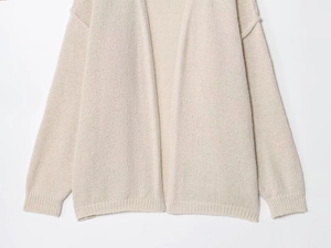 Dettaglio del cardigan in maglia beige che mostra la trama a maglia grossa e i polsini