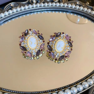 Close-up of vintage cameo earrings with purple rhinestones on a pearl mirror tray