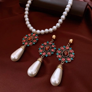 Detailed shot of vintage gold pearl necklace and earrings set on red silk fabric