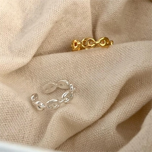 Macro shot of silver and gold anchor chain rings on beige woven texture background