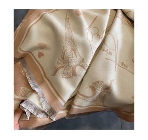 Close-up of beige cashmere-feel scarf with Eiffel Tower pattern and tassel edges