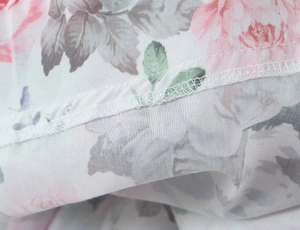 Makroansicht der Overlock-Stichdetails am Rand eines Kleides mit Blumenmuster