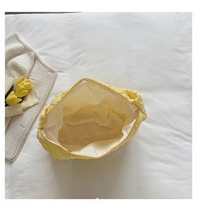 Interior view of yellow quilted makeup bag showing spacious beige lining and structure