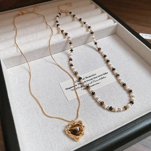 Close-up of 18K gold tiger eye heart necklace set on beige jewelry box display
