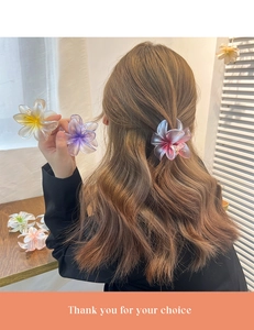 Elegant floral plumeria hair claw clip shown in multiple colors on a model hair style