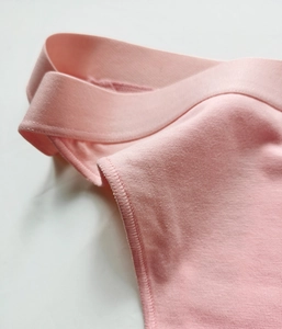 Detailed close-up of pink cotton fabric seams and elastic waistband on women's briefs