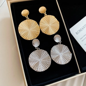 Detailed view of large round geometric textured earrings in gold and silver finishes
