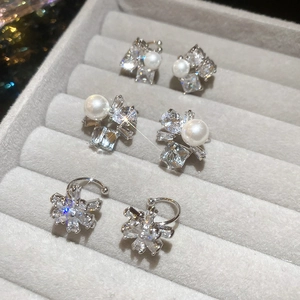 Detail of three pairs of silver zircon and pearl stud earrings on a gray velvet tray