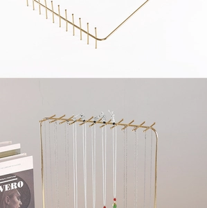 Close-up of golden metal jewelry rack with multiple hooks for necklace display