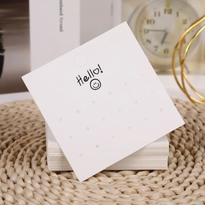 Detail of white jewelry display card with Hello greeting and smiley face on a woven mat