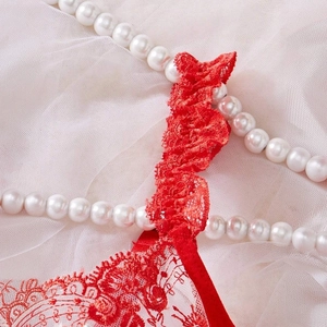 Detailed macro view of the delicate red floral lace and pleated ruffle texture on the bra