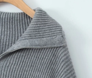 Detailed close-up of grey ribbed knit sweater collar and functional silver zipper texture