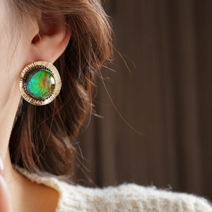 Detailed close-up of vintage golden round earrings featuring vibrant emerald green resin