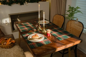 Detail view of a classic red and green plaid fabric placemat on a festive wooden dinner table