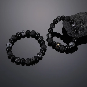 Star charm bracelets with black onyx and volcanic stone beads on reflective surface