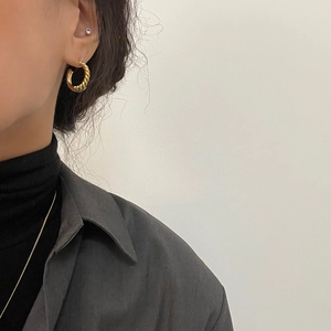 Minimalist twisted gold C-shaped hoop earrings with woven texture on model