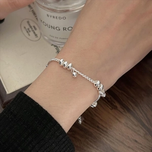 Macro view of minimalist 925 sterling silver beaded bracelet on wrist with elegant decor