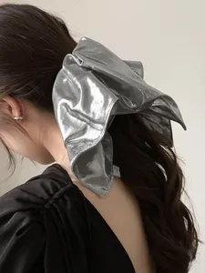 Detail of a large silver metallic bow hair clip on dark wavy hair for an elegant look