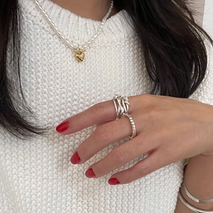 Detail of layered silver winding ring and gold heart pendant pearl necklace on model