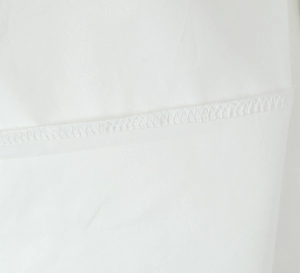Vue macro détaillée de la texture du tissu blanc et des coutures de précision sur la robe
