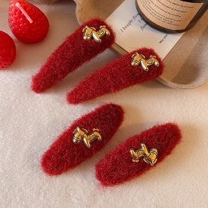 Dettaglio di fermagli per capelli in peluche rosso con piccoli motivi a forma di pony