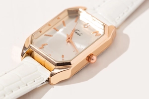 Detail view of stylish rose gold octagonal quartz watch with white leather strap