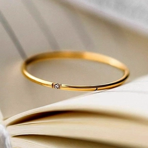 Macro view of a minimalist 18K gold plated ring with a single diamond in a book