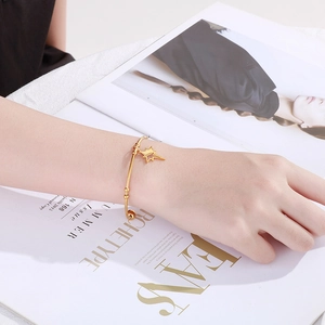 Close-up of a gold star charm bangle worn by a model on a lifestyle magazine background
