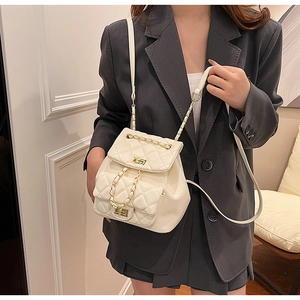 Close-up of white quilted leather backpack with gold chain strap and turn-lock closure