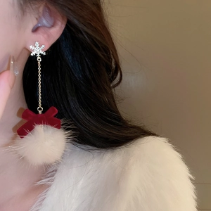 Detail showing red velvet bow and white pompom on silver snowflake tassel earrings