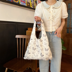 Detailed texture of plush white tote bag with gray butterfly print in a cozy setting