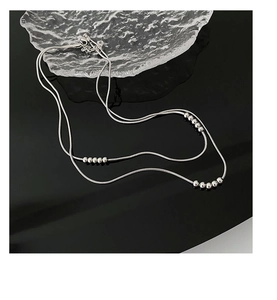 Close-up of silver snake chain with beads, adjustable lobster clasp on mirror surface