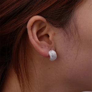 Macro view of silver teardrop earring with frosted matte texture and hammer finish