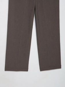 Gros plan détaillé montrant la texture du tissu sergé et les coutures du pantalon marron