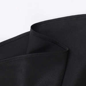 Détail du tissu en satin noir montrant des coutures fines et une texture textile lisse