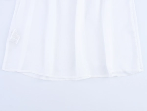 Detail showing the hemline and care label of white hollow out long sleeve blouse