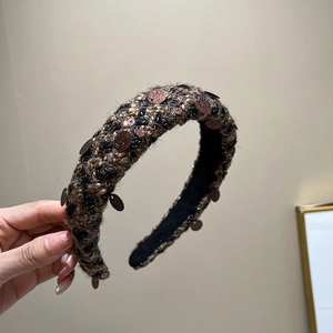 Detail of dark brown braided headband with sequin accents and thick retro weave texture