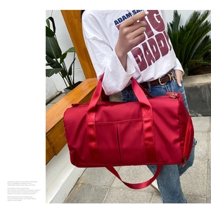 Detail of red nylon travel bag showing durable handles and adjustable shoulder strap