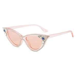 Pink cat eye sunglasses with rhinestones and blue teardrop gemstones on white background