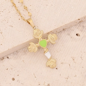 Macro detail of gold cross pendant with green heart and white rose enamel inlay