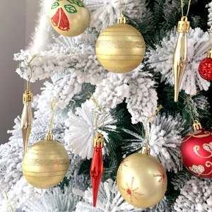 Dettaglio di palline di Natale festose oro e rosse con ornamenti su un albero innevato